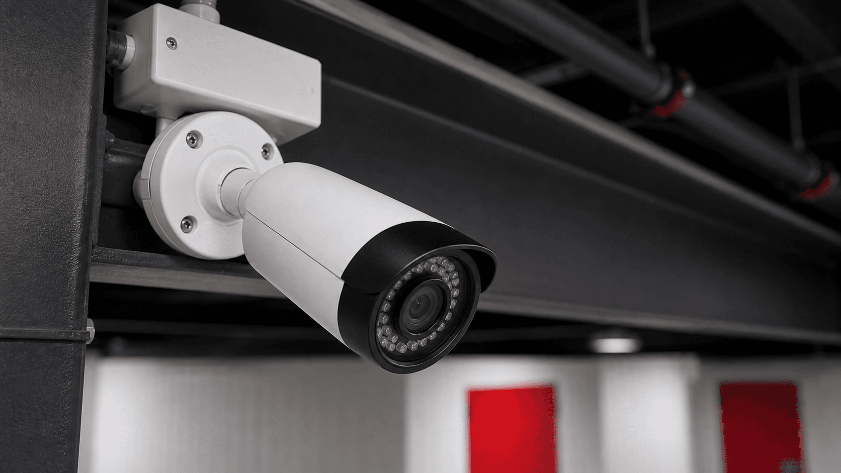 Security camera monitoring a clean self-storage corridor with red unit doors